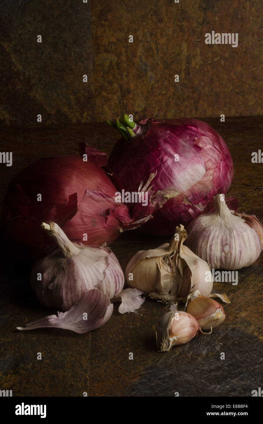 detail of red onions and garlic over a stone textured table. still life Stock Photo