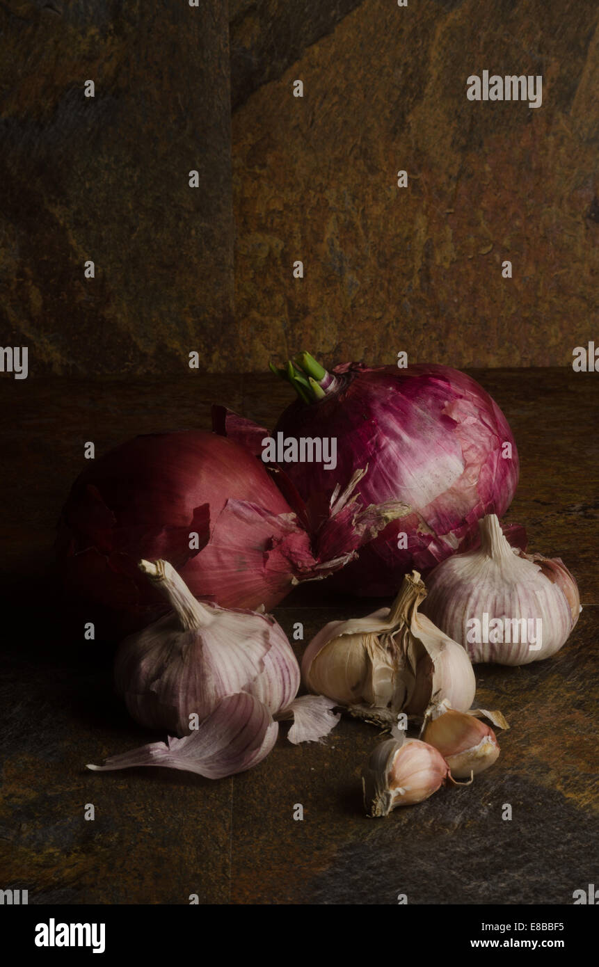 detail of red onions and garlic over a stone textured table. still life Stock Photo