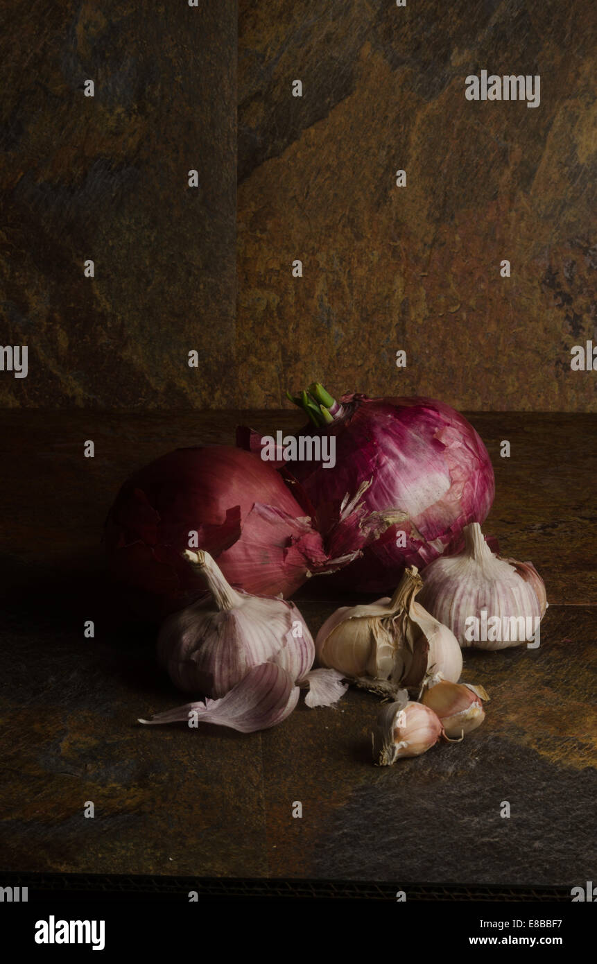 detail of red onions and garlic over a stone textured table. still life Stock Photo