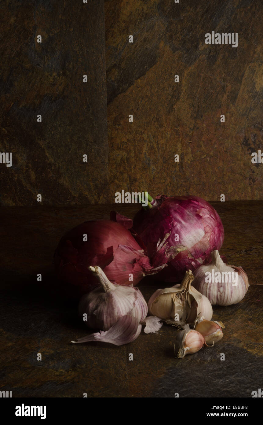 detail of red onions and garlic over a stone textured table. still life Stock Photo