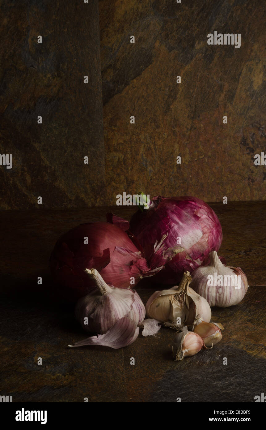 detail of red onions and garlic over a stone textured table. still life Stock Photo