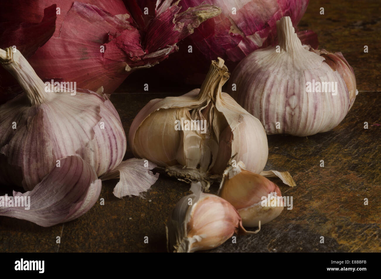 detail of red onions and garlic over a stone textured table. still life Stock Photo