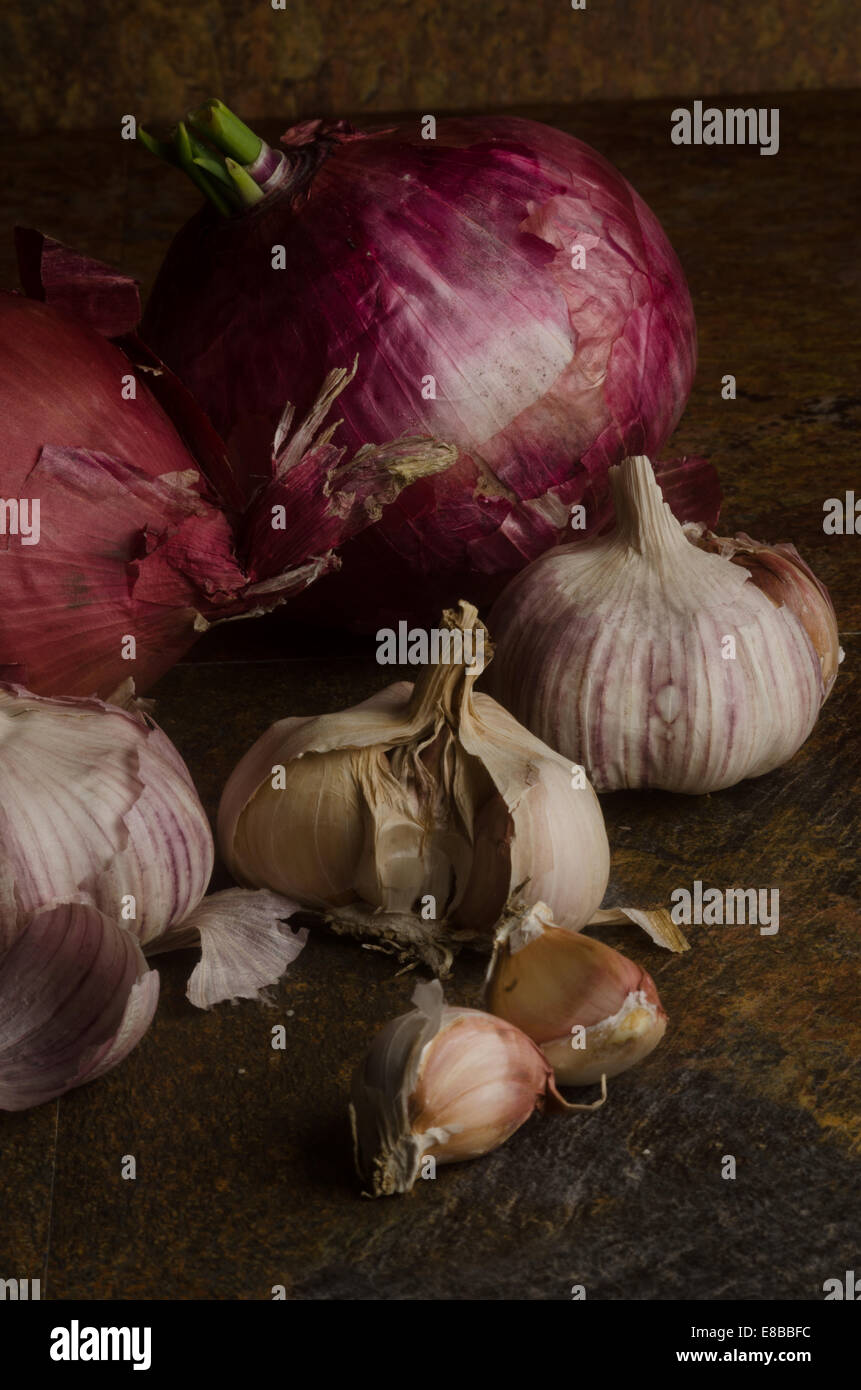 detail of red onions and garlic over a stone textured table. still life Stock Photo