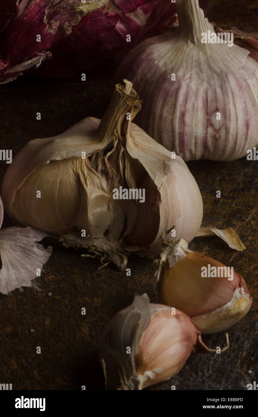 detail of red onions and garlic over a stone textured table. still life Stock Photo