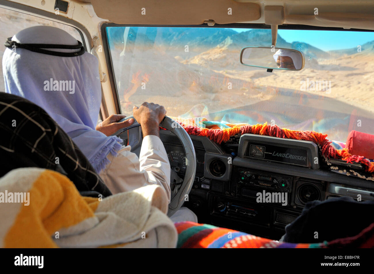 Bedouin man driving LandCruiser across desert south Sinai Peninsula, Egypt. Wearing robe and kufeya with igal headwear Stock Photo