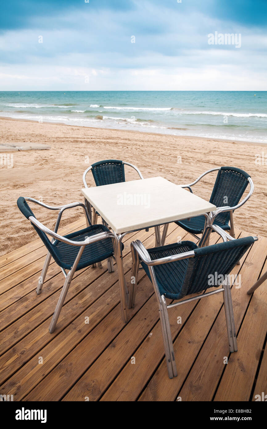 Open space sea side bar interior with wooden floor and metal armchairs on the sandy beach Stock Photo