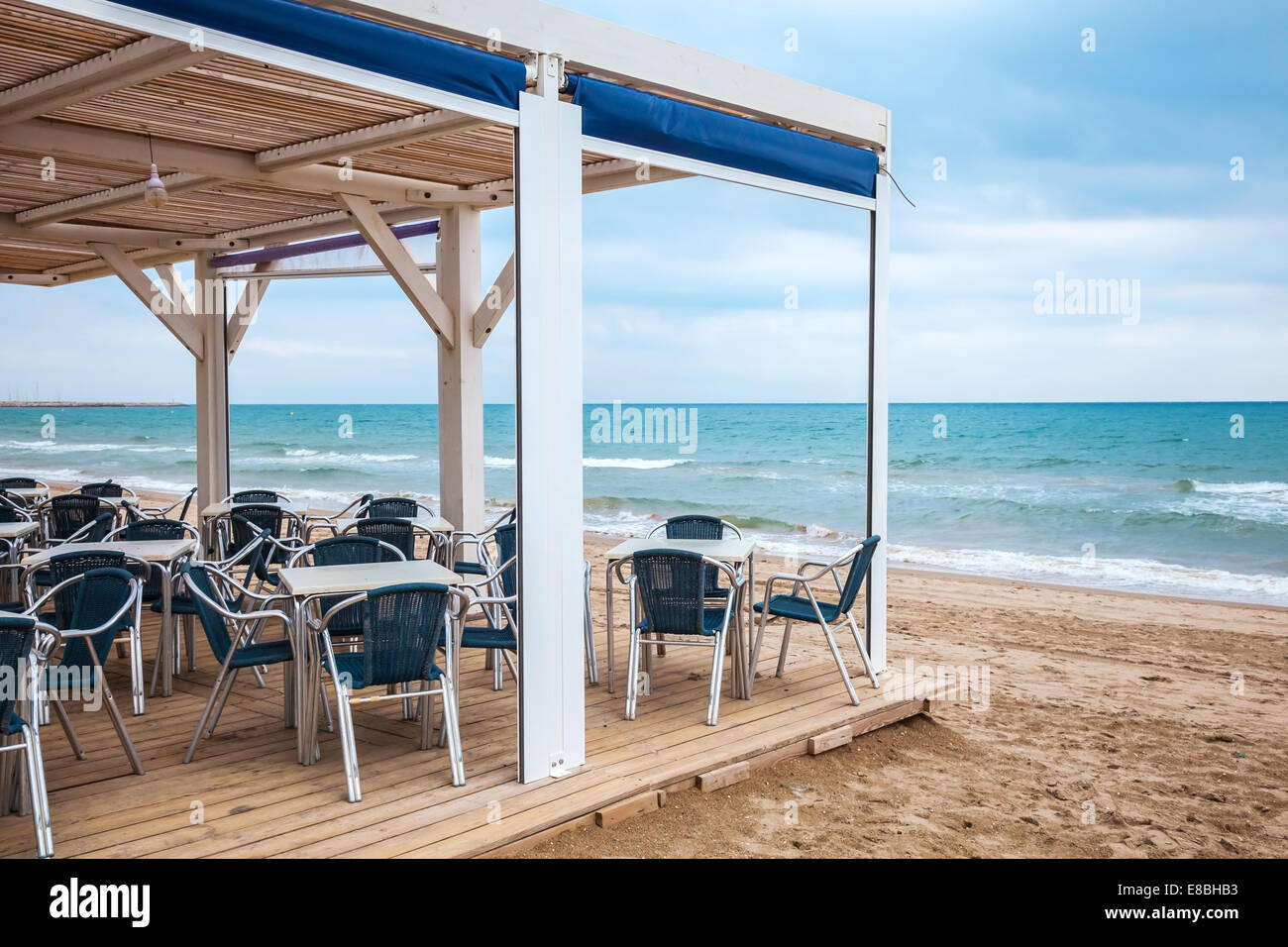 Sea side bar interior with wooden floor and metal armchairs on the sandy beach Stock Photo
