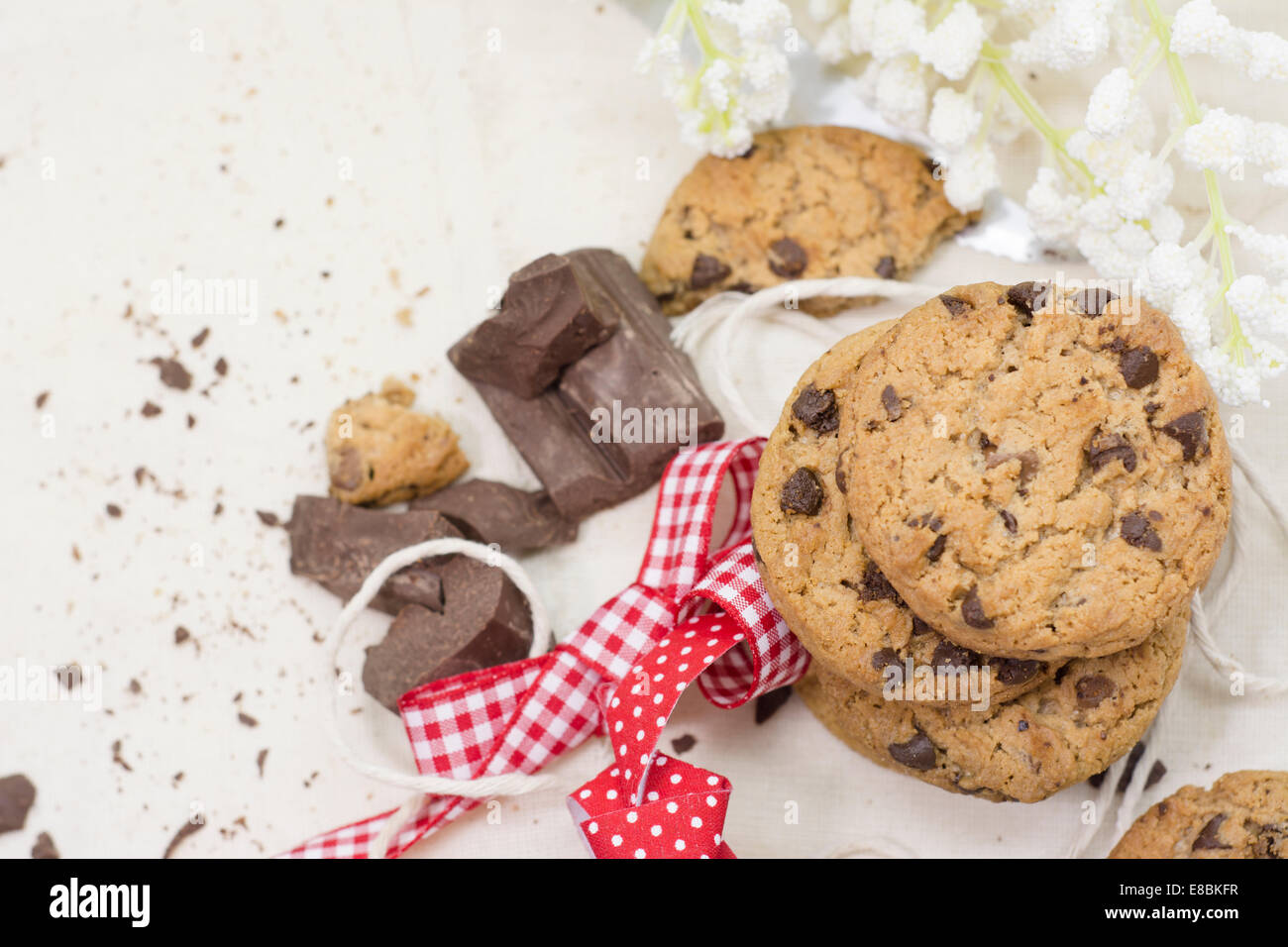 Cookies, chocolate chips on red ribbon rustic tablecloth and flowers ...
