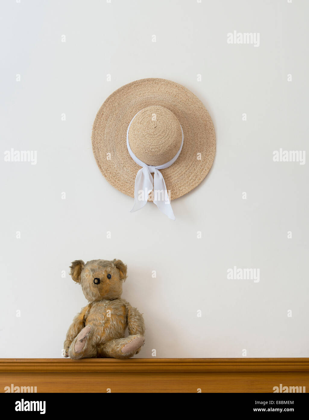 Threadbare One Eyed Teddy bear and a womans straw hat Stock Photo