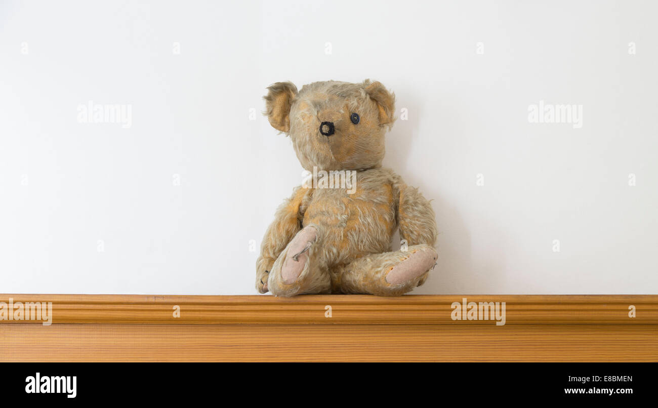 Threadbare One Eyed Teddy bear on a wooden shelf Stock Photo