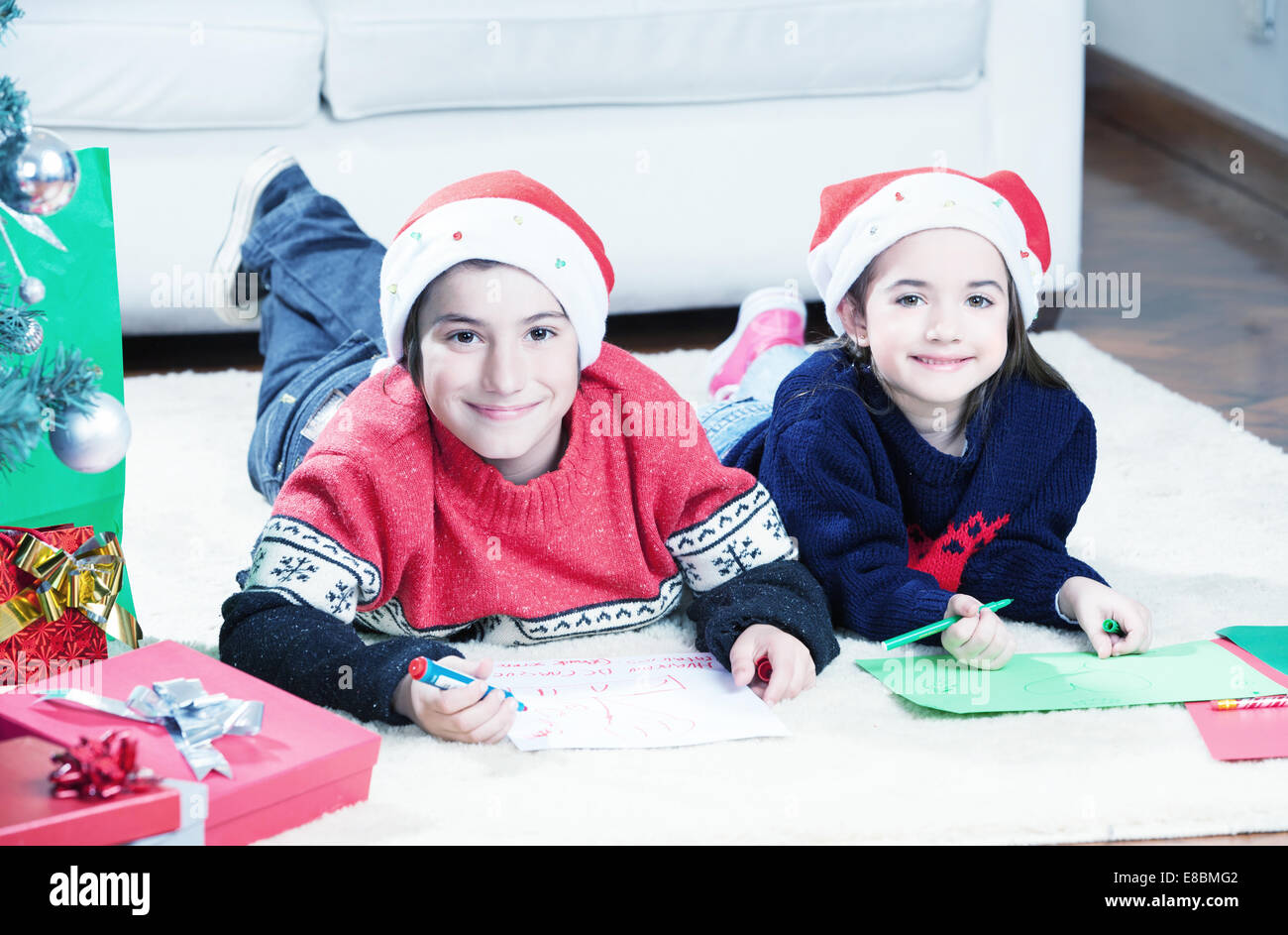 Brother and sister laying down enjoying gifts for Christmas day. Stock Photo