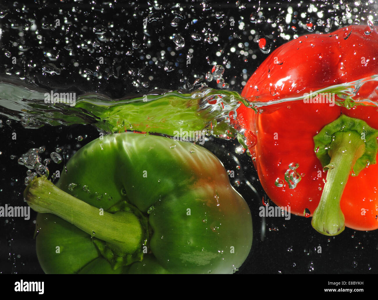 Red and green bell peppers dropped in water to create a splash Stock Photo Alamy