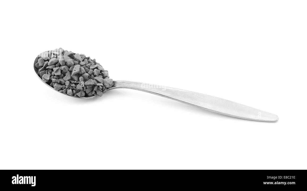 Metal teaspoon measure of instant coffee granules, isolated on a white background - monochrome processing Stock Photo