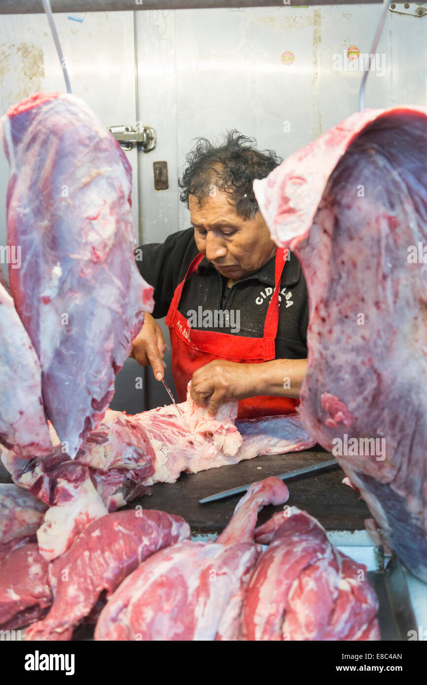 Local Peruvian man, stallholder butchering meat at a stall at Surquillo Market, Miraflores, Lima, Peru Stock Photo