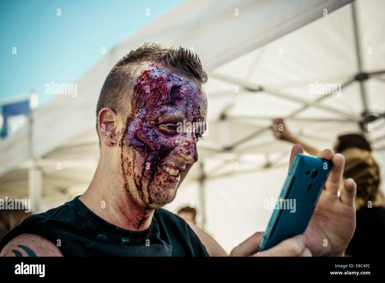 Sitges, Spain. 4th Oct, 2014. A man sees his zombie makeup on his smart phone in front of the Sitges Zombie Walk 2014 Credit:  Matthias Oesterle/ZUMA Wire/ZUMAPRESS.com/Alamy Live News Stock Photo