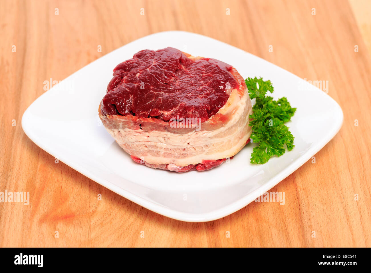 Two 8oz filet mignon beef steaks wrapped with bacon on a wood cutting board. Stock Photo