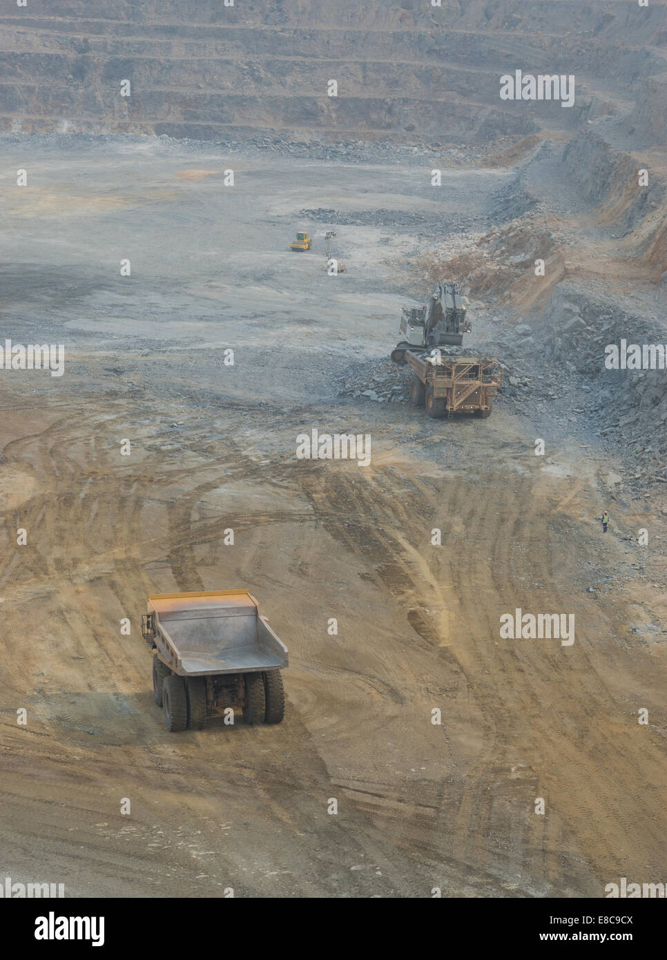 A big Liebherr excavator loads haul trucks with ore at a large open cast African copper mine whilst a Caterpillar truck waits. Stock Photo