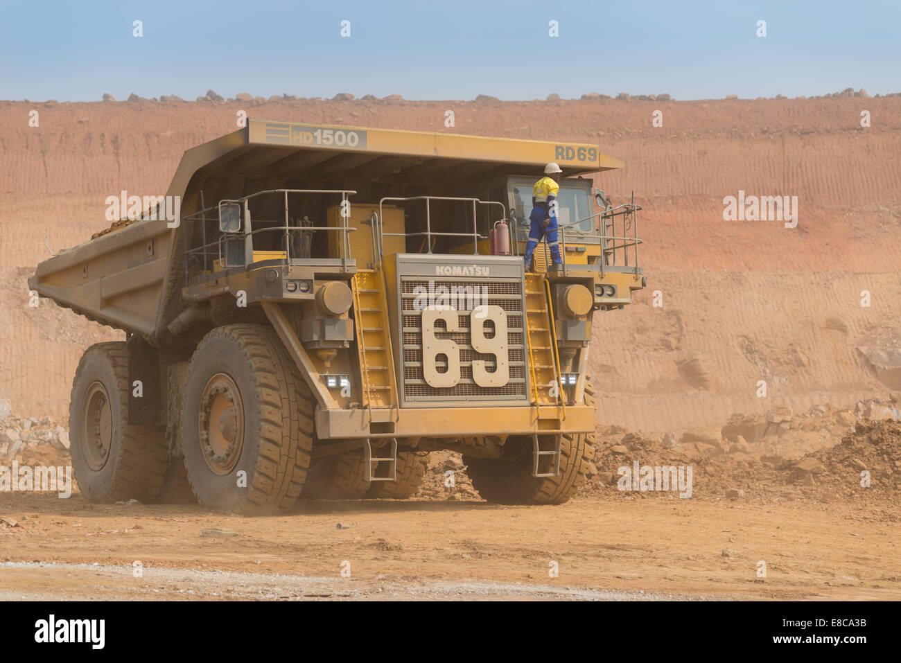 An operator climbs up to the cab of his large Komatsu mining truck in an African open cast copper mine. Stock Photo