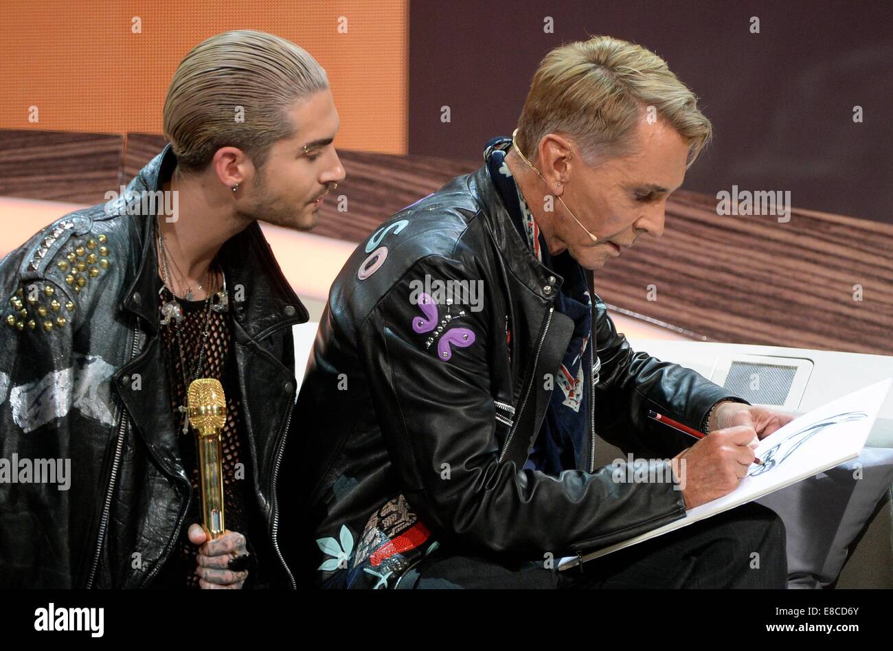 Erfurt, Germany. 5th Oct, 2014. German fashion designer Wolfgang Joop (R) draws as Tokio Hotel singer Bill Kaulitz looks over his shoulder during the ZDF show 'Wetten, dass.?' in Erfurt (Thuringia), Germany, 04 October 2014. Credit:  dpa picture alliance/Alamy Live News Stock Photo