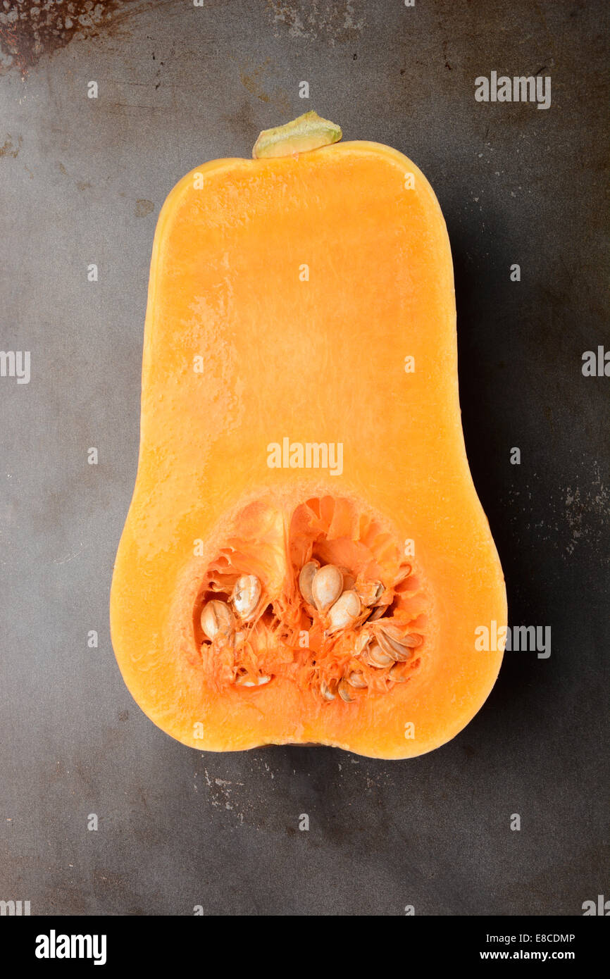 Butternut Squash on a metal cooking sheet. The vegetable is cut in half showing the inside. Vertical format. Stock Photo