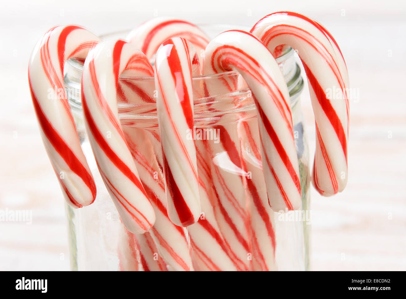 Closeup of a bunch of holiday candy canes hooked on the rim of a glass