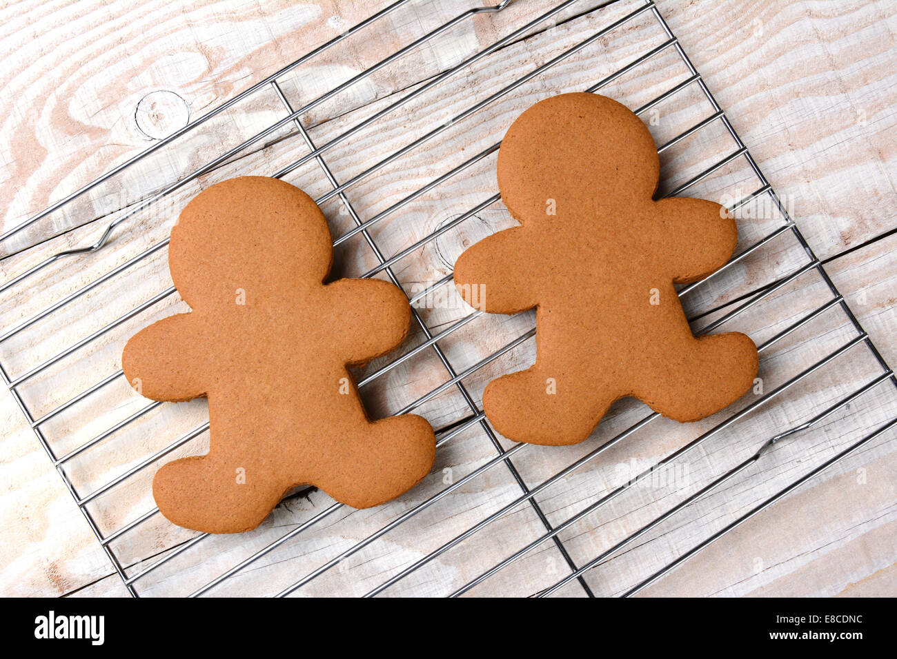 HIgh angle view of two gingerbread men on a cooling rack. The wire rack is on a rustic white kitchen table. The cookies are  pla Stock Photo