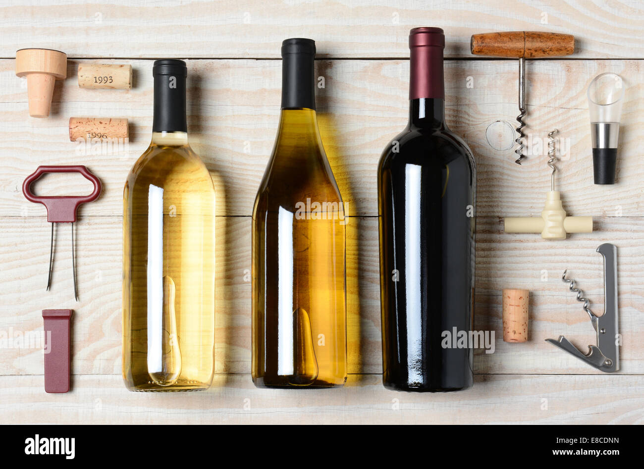 High angle shot of three wine bottles surrounded by accessories such as corkscrews, stoppers, pourers and corks. Horizontal form Stock Photo