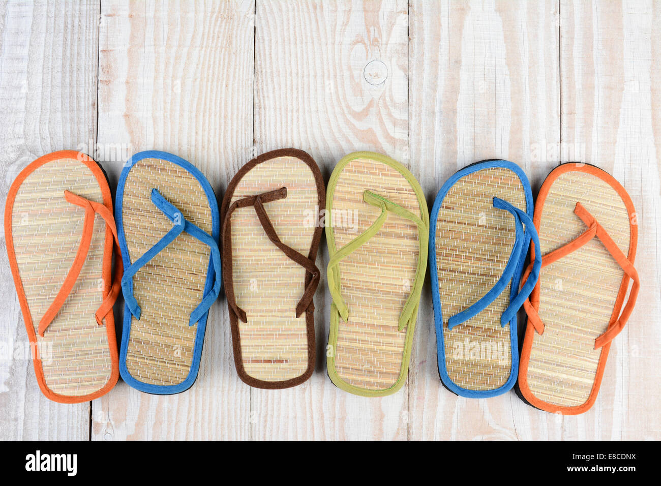 Mismatched Flip Flop sandals on a wooden deck. High angle shot of ...