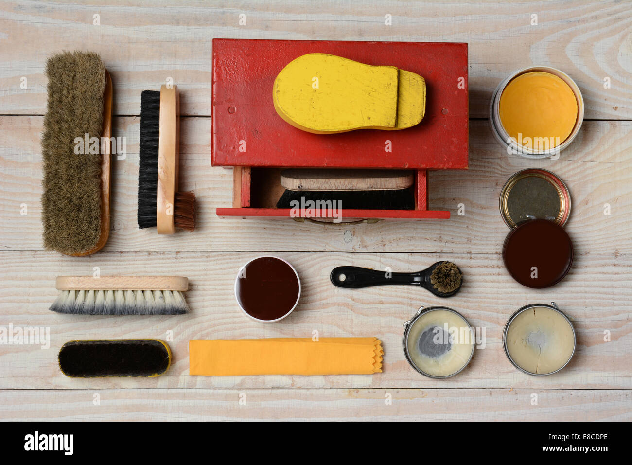 High angle view of  an antique shoe shine kit and its accessories, including brushes, polish, and buffing cloth. Horizontal form Stock Photo