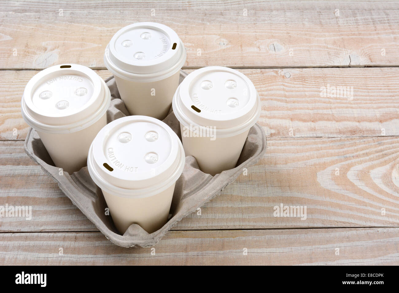 High angle shot of a cardboard take out tray with four coffee cups with lids. Stock Photo