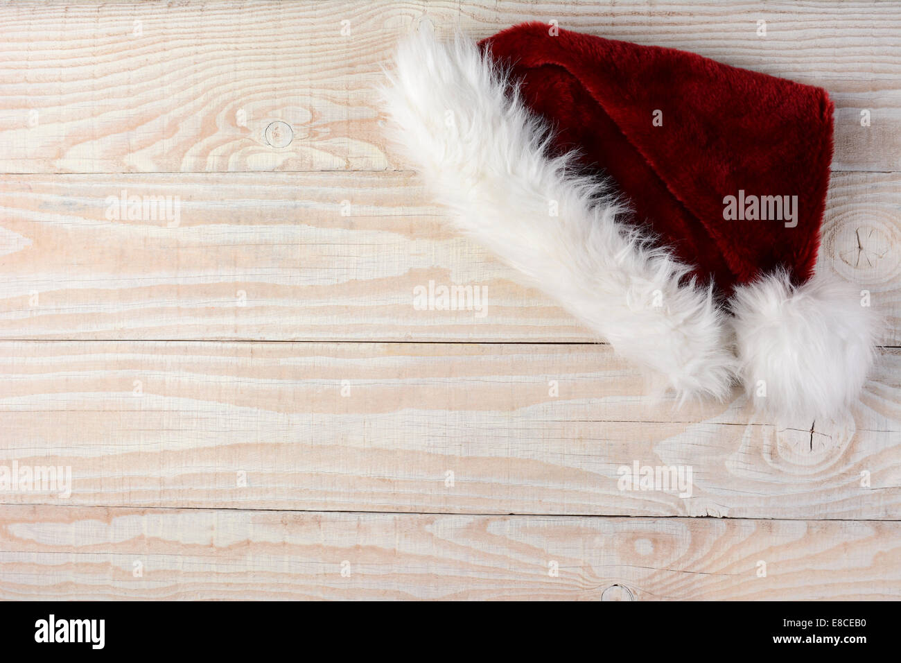 High angle shot of a Santa Hat on a white wood table. Horizontal format with the hat in the upper right corner leaving room for Stock Photo