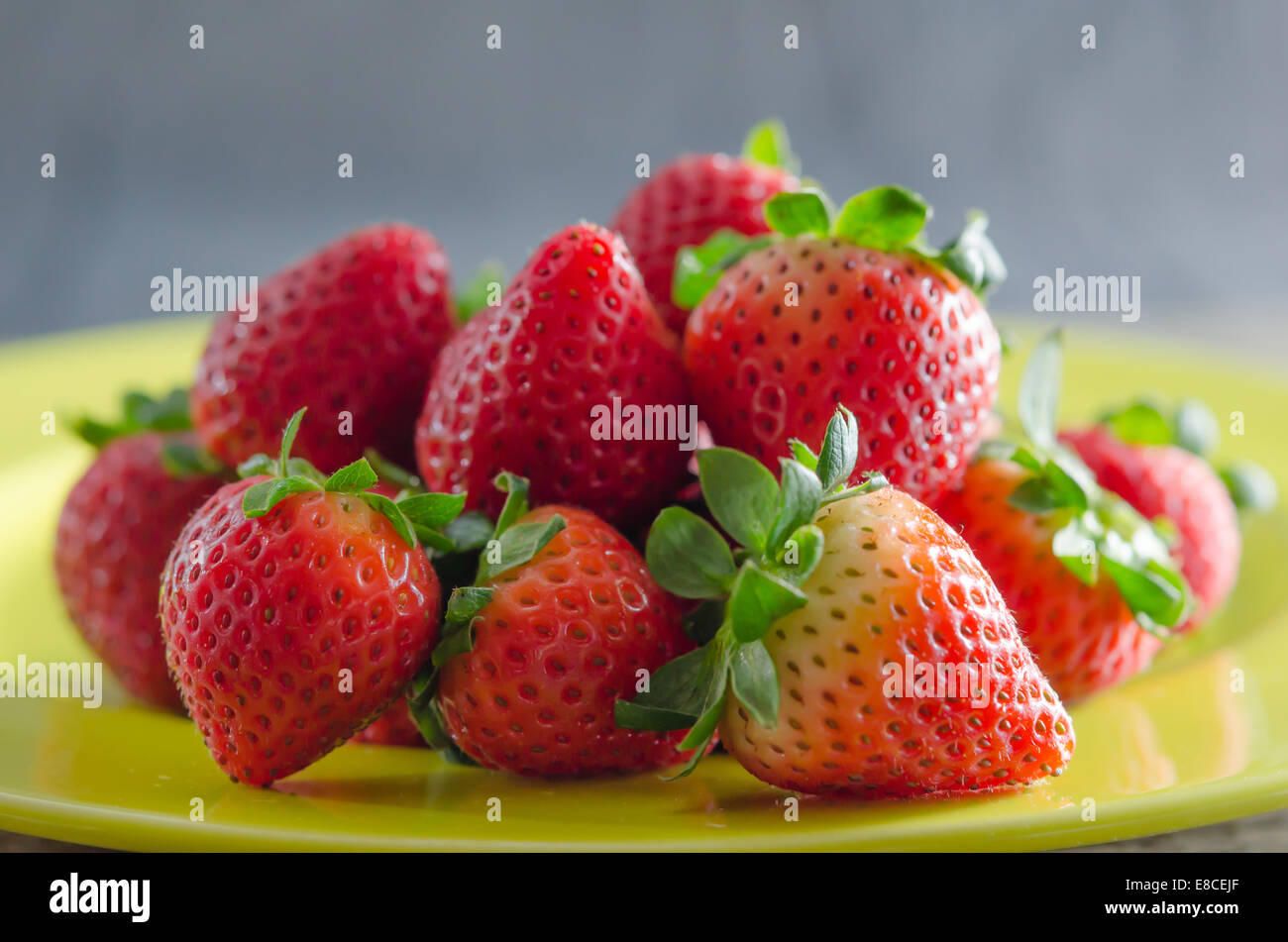 still life of fresh red strawberries on dish over wooden background ...