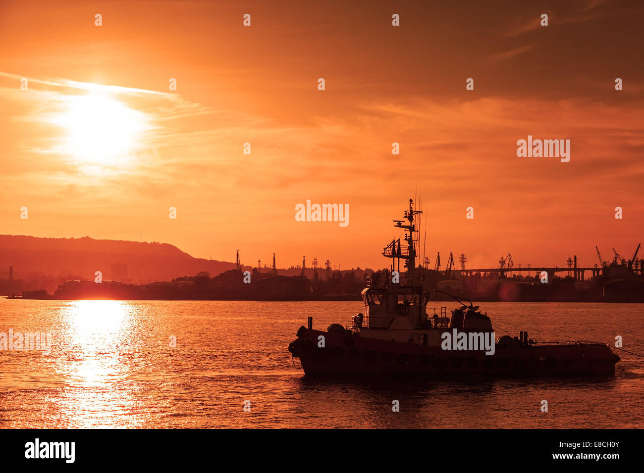 Tug is underway on Black sea at sunset, Varna harbor, Bulgaria Stock Photo