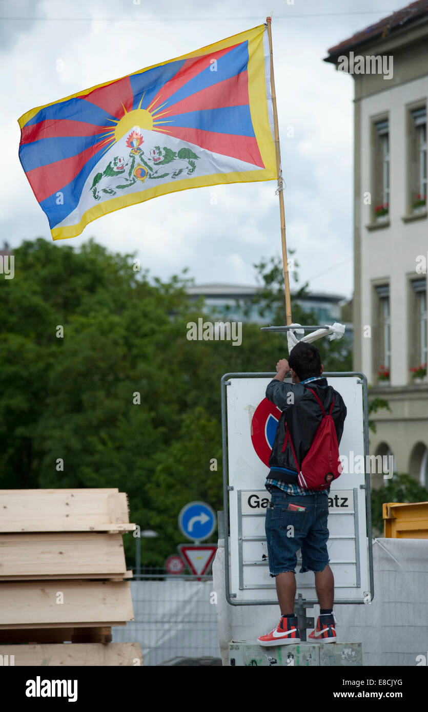 A Tibetan is attaching the flag of Tibet onto a traffic sign at a protest rally in Bern, Switzerland Stock Photo