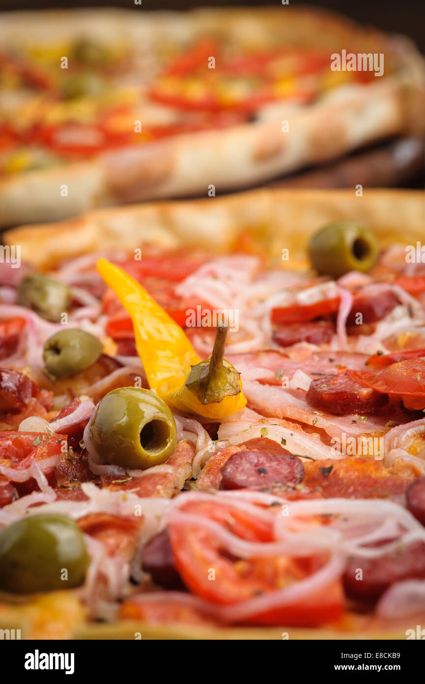 Pizza with tomato, salami, peppeeoni, olives and yellow hot pepper Stock Photo