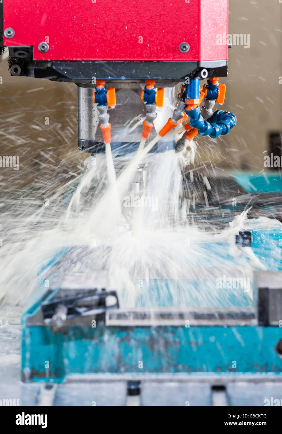 A water-cooled CNC milling cutter 'in action' while producing a custom aluminum spare part Stock Photo
