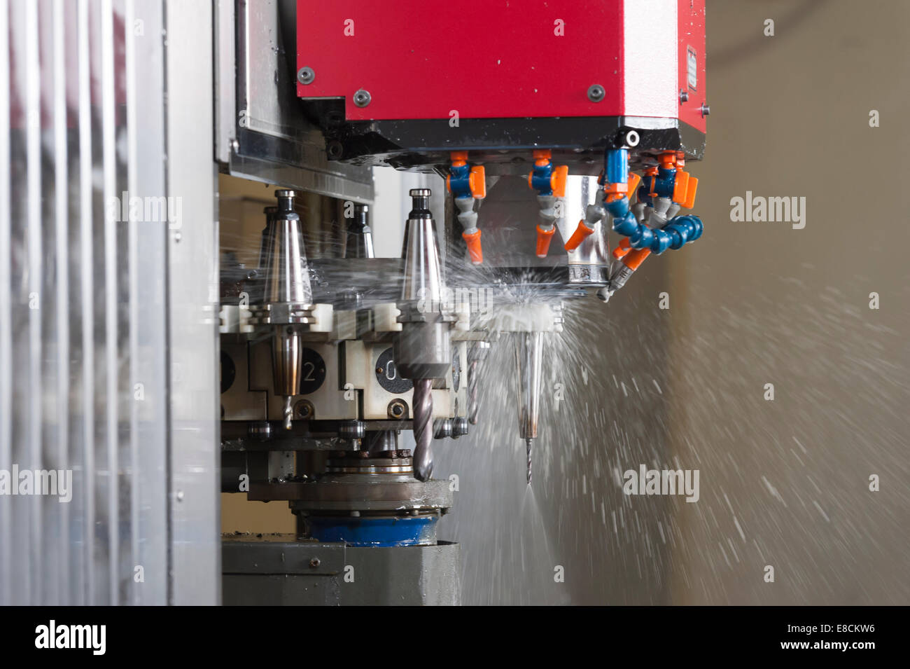 A CNC milling cutter is automatically changing its tooltip during production of a custom aluminum spare part Stock Photo