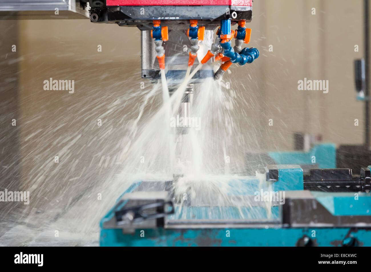 A water-cooled CNC milling cutter 'in action' while producing a custom aluminum spare part Stock Photo