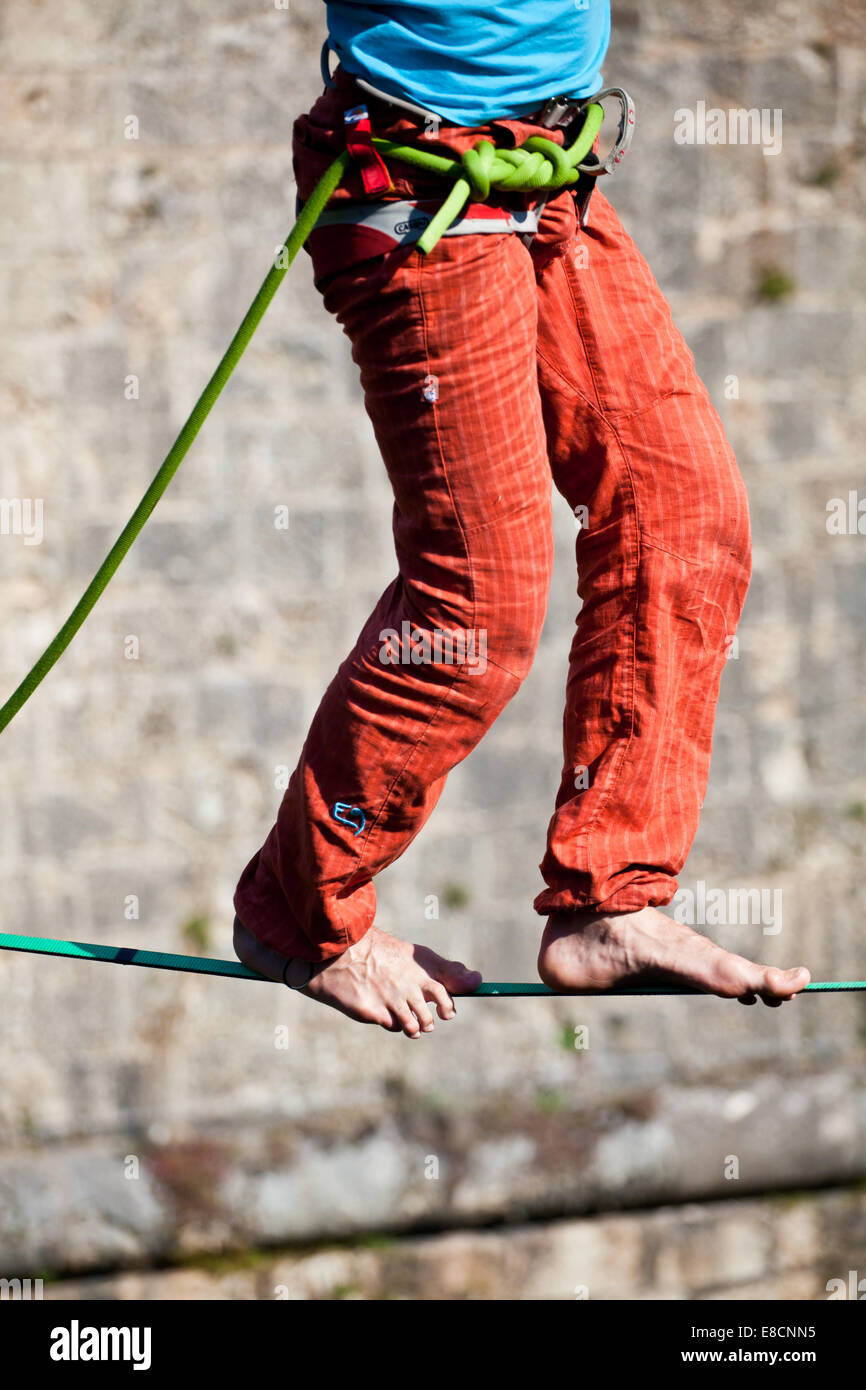 Slacklining is a practice in balance that typically uses nylon or polyester webbing tension between two anchor points. Stock Photo
