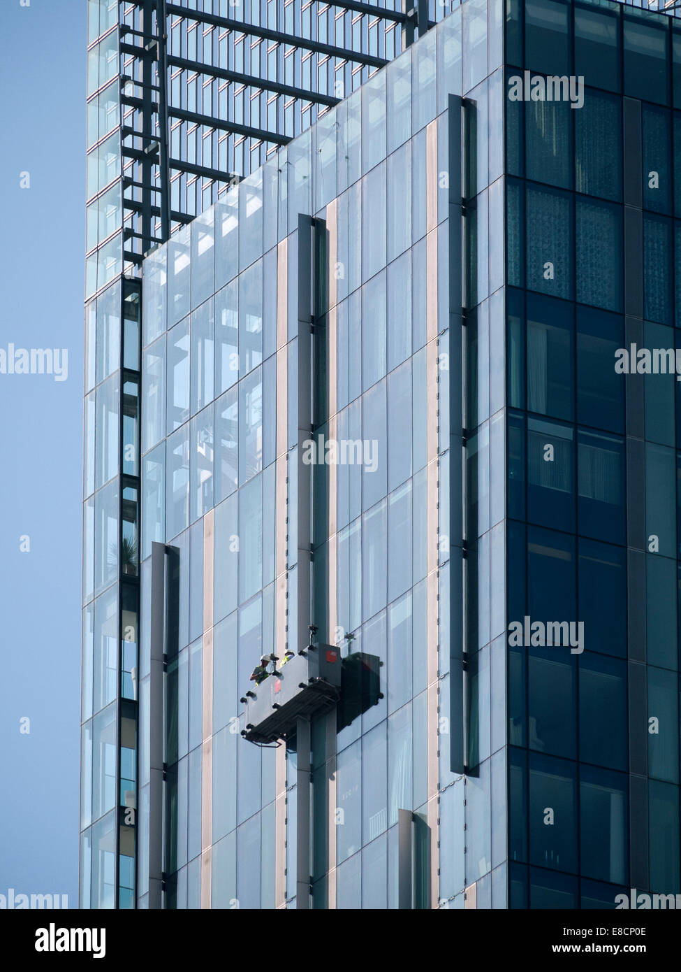 Window cleaners in a suspended cradle near the top of the Beetham Tower, Manchester, England, UK