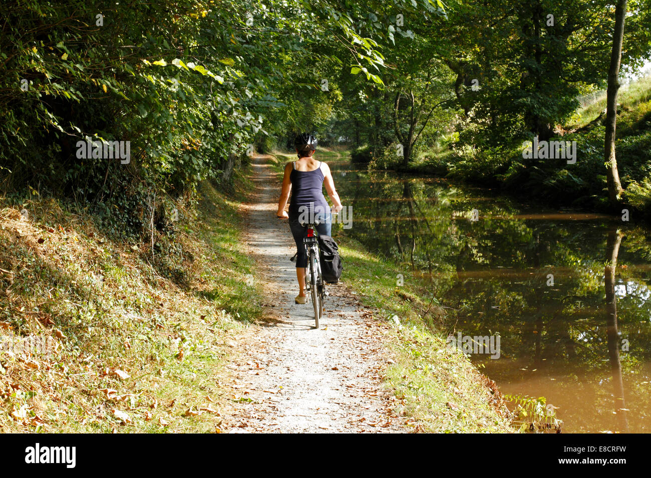 Young woman Cycling along a canal towpath Stock Photo