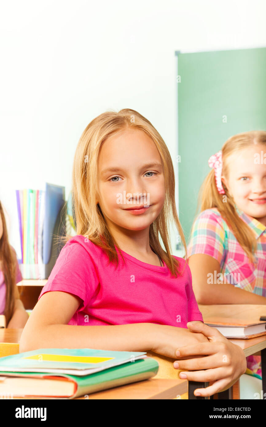 Small girl in pink tshirt sits at desk and looks Stock Photo