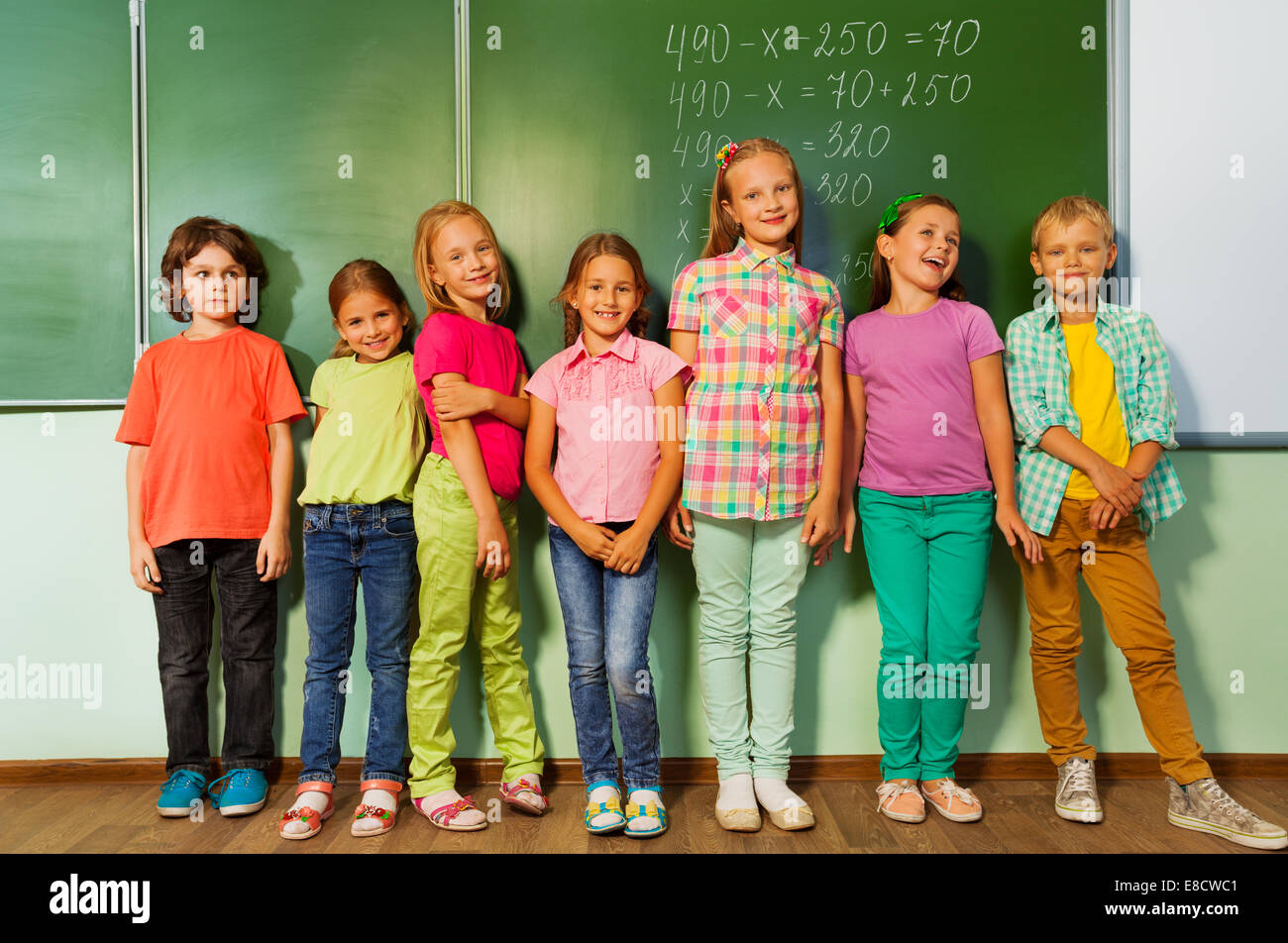 Kids stand in line near the blackboard and smile Stock Photo Alamy