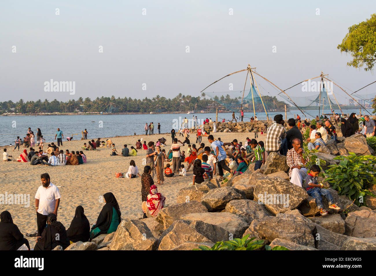 PORT KOCHI OR COCHIN INDIA EVENING CROWDS GATHER ON THE BEACH NEAR THE CHINESE FISHING NETS Stock Photo