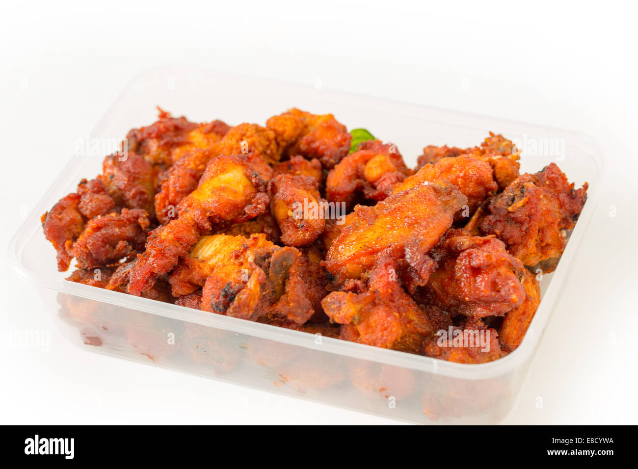 Indian Chicken 65 nuggets in a takeaway plastic pot, a favourite light spicy snack in the subcontinent Stock Photo