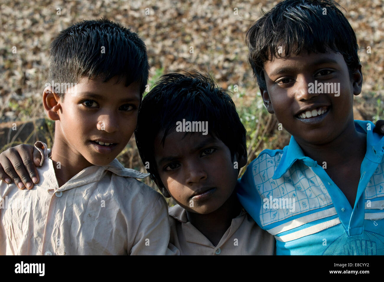Three young Indian village boy children arm in arm good friends ...
