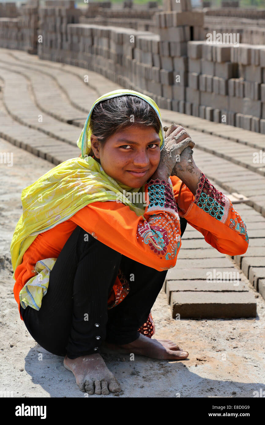 female brickyard worker (14 years old) form clay bricks on a field of