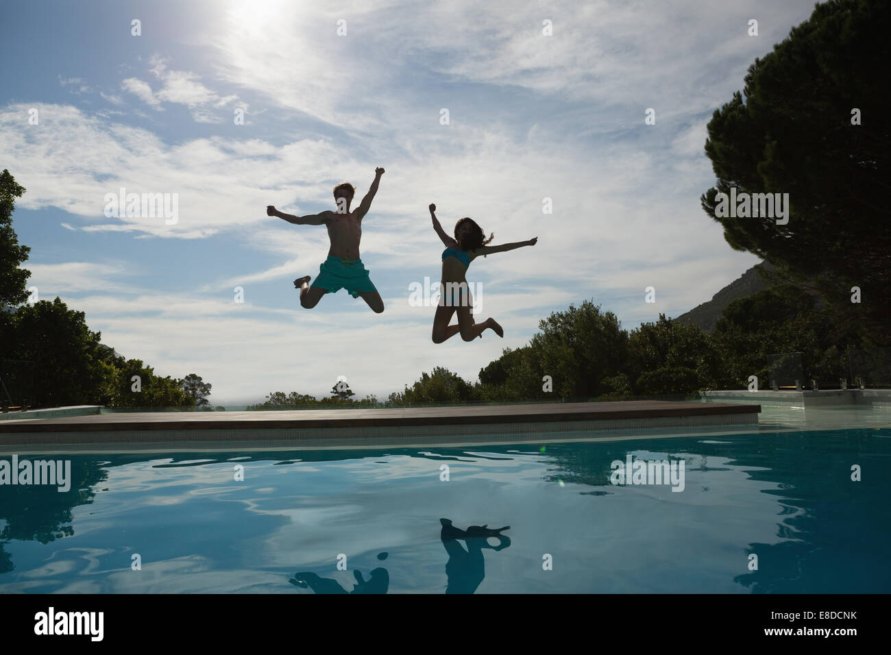 Couple jumping into swimming pool Stock Photo