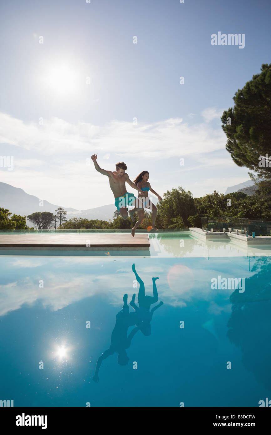 Cheerful couple jumping into swimming pool Stock Photo