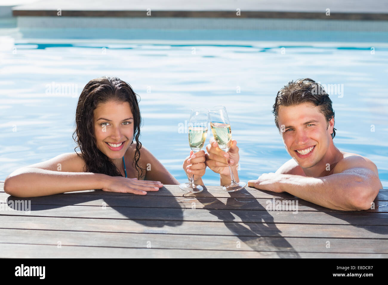 Couple toasting champagne in swimming pool Stock Photo